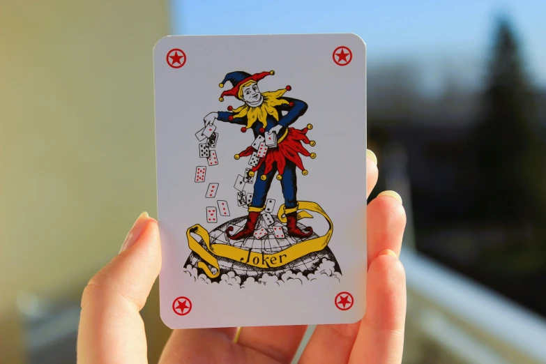 a joker playing card in a hand with chinese writing