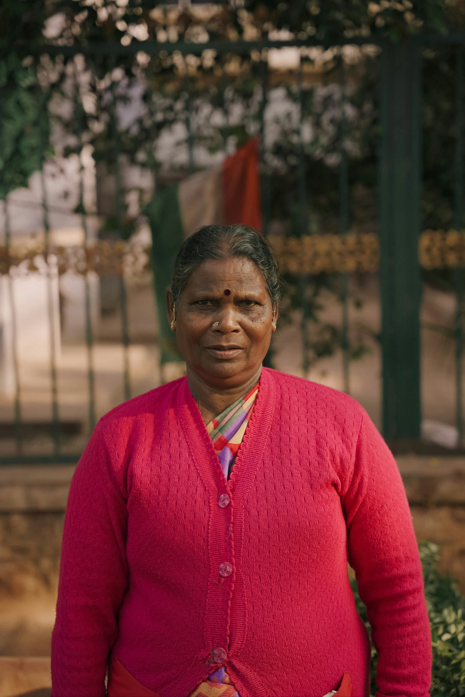 an older woman standing in front of a tree