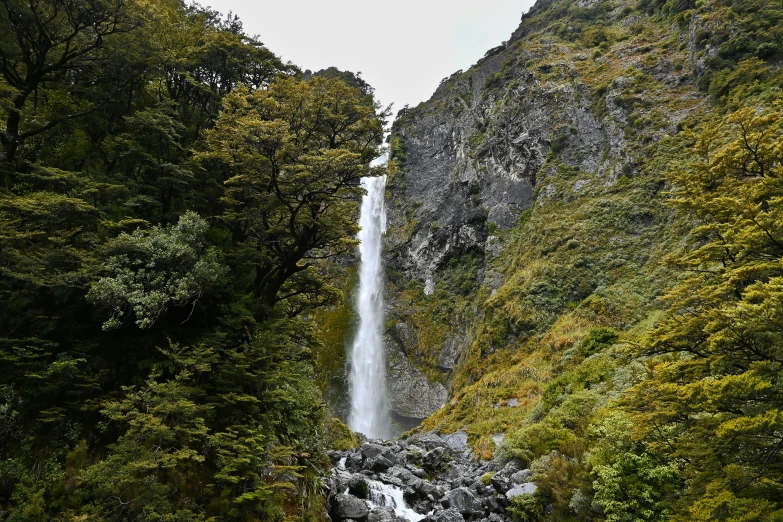 an image of waterfall in the forest with people under it