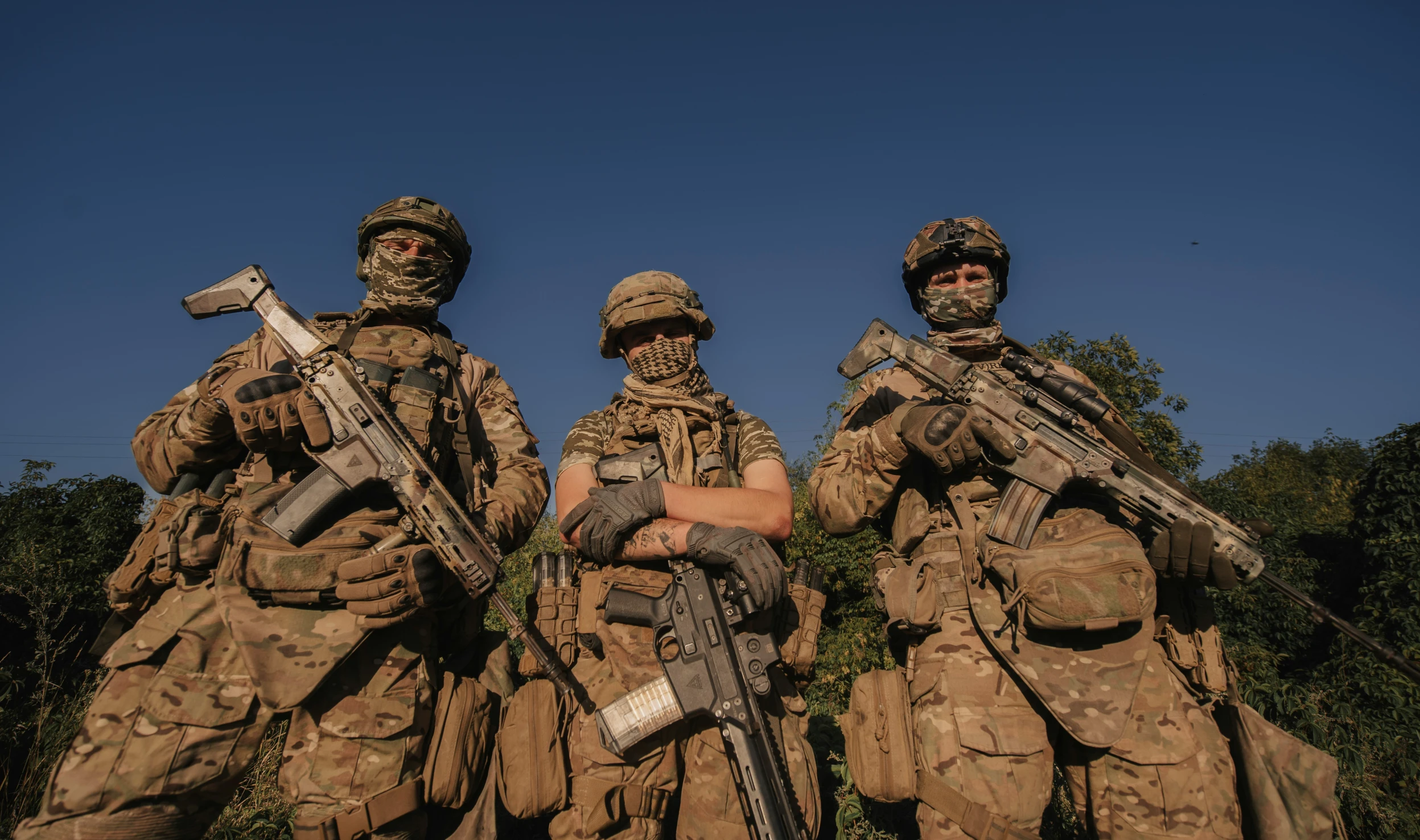 three armed soldiers stand in formation holding weapons