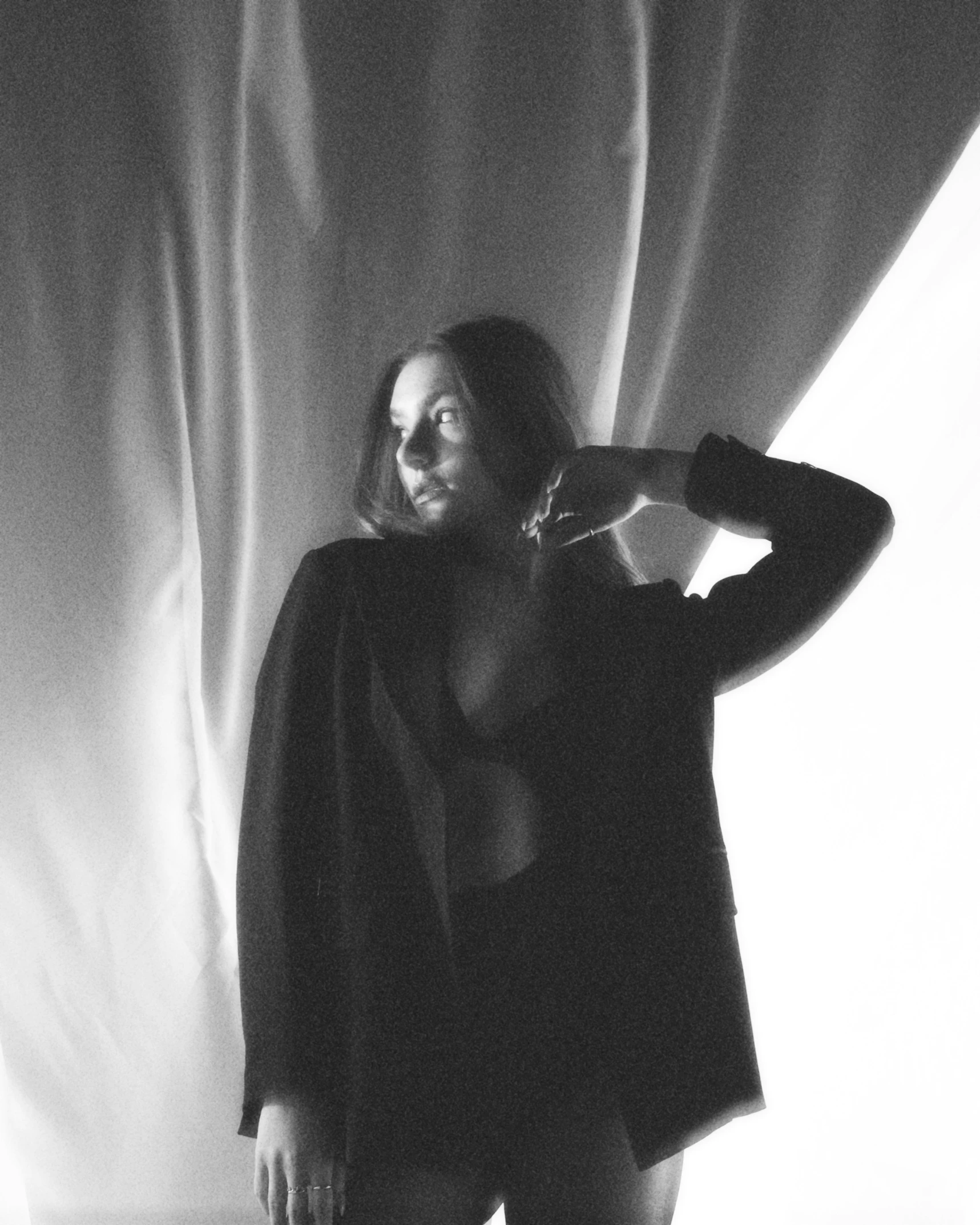 a black and white pograph of a woman posing in front of curtains