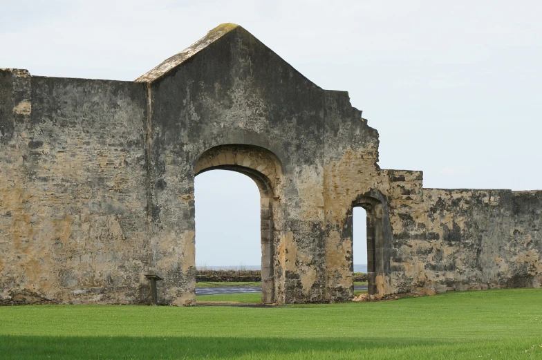 an old building on the side of a grassy hill