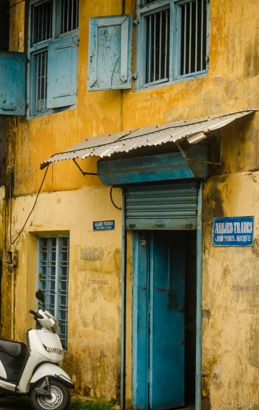 a motor scooter parked in front of a yellow building