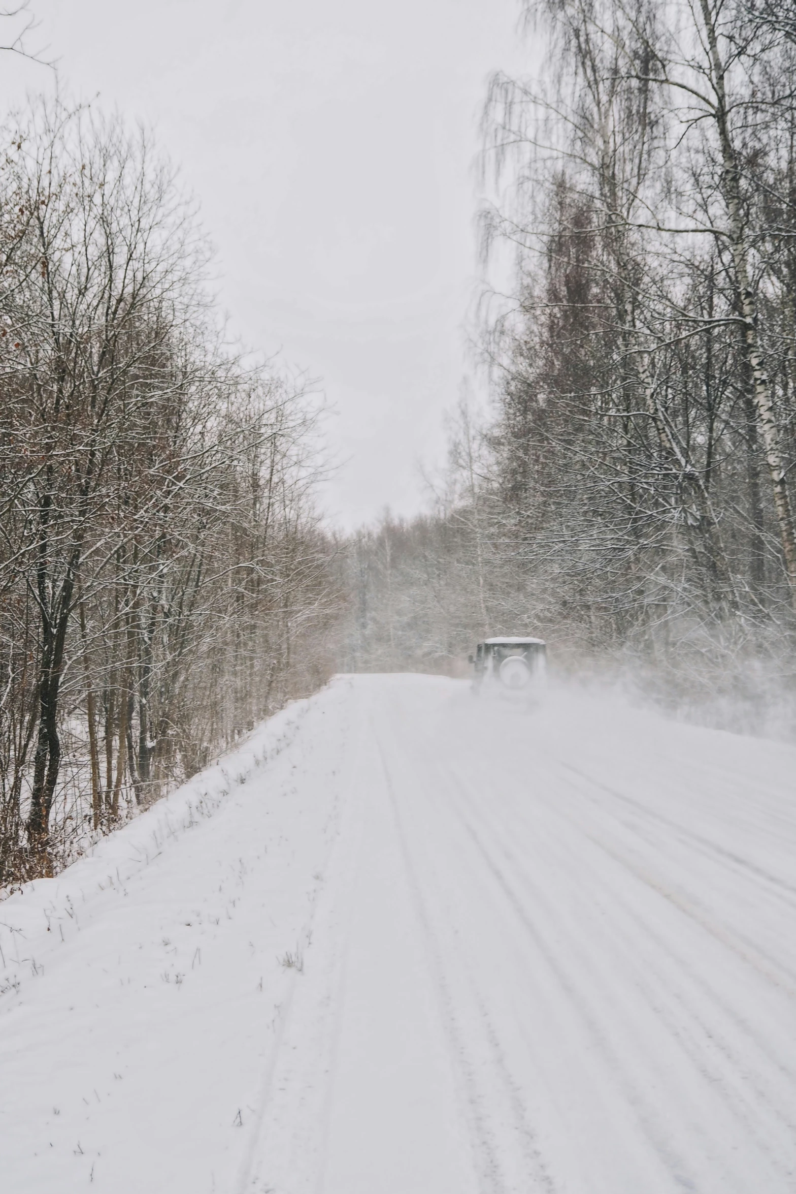 a vehicle traveling through snow covered trees on a highway