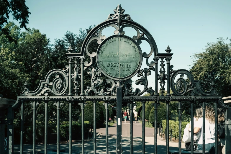 a black gated street with a white clock and person standing at the end