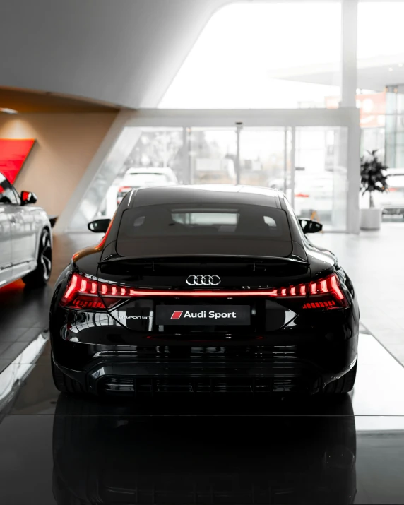 the rear of two shiny audi cars, in a dealership