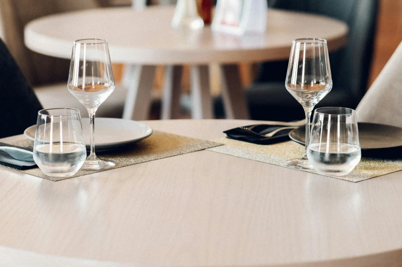 an arrangement of dishes and wine glasses sit upon a table