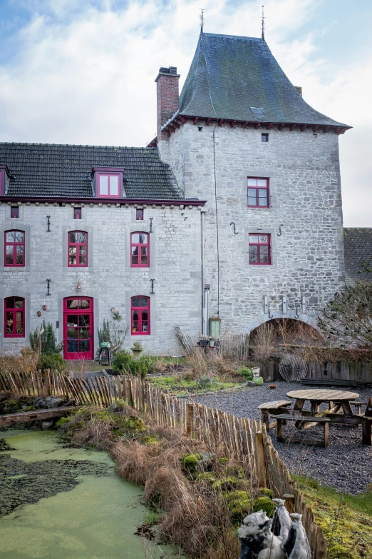 the white building has red windows and is next to water