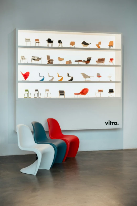 colorful chairs sitting in front of a white wall