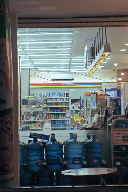 an oil store with bottled water, a soda machine and blue pots