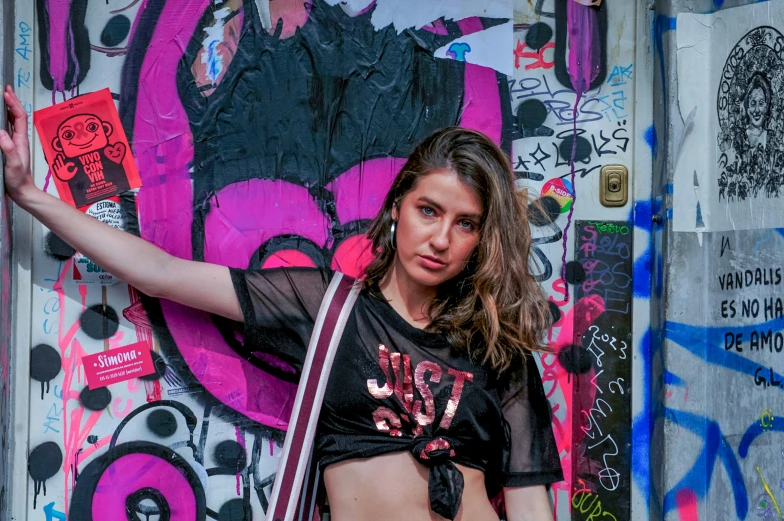 girl in black t - shirt and jeans near a wall with graffiti