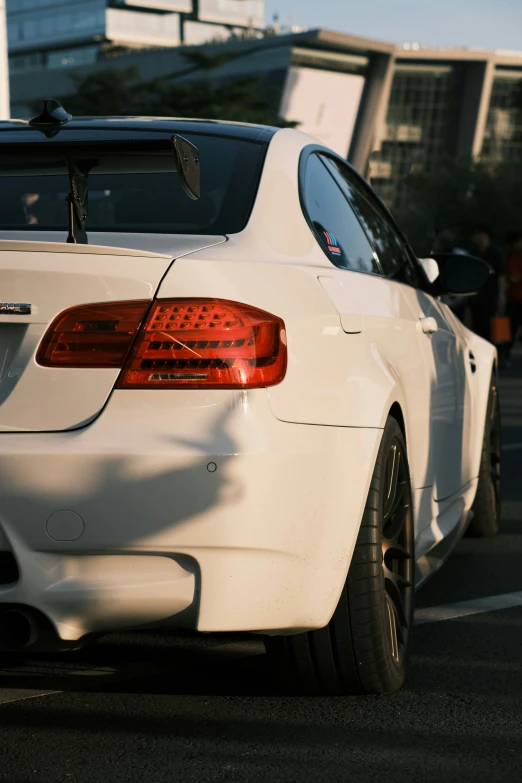 an all white bmw with orange lights in a parking lot