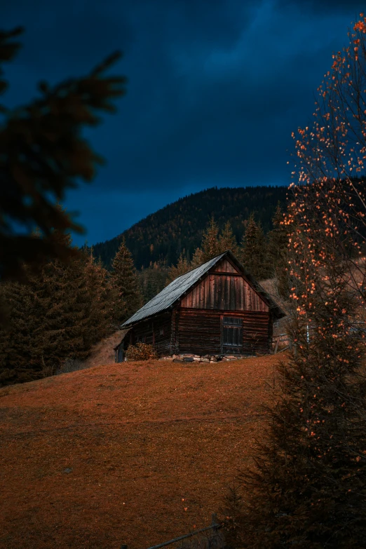 a log cabin nestled in the woods under a cloudy night sky