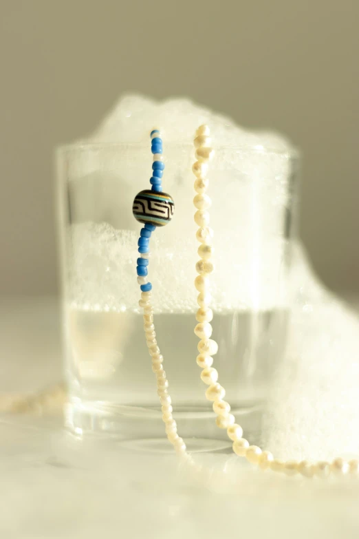 a beaded necklace with a blue and white bea on top of ice