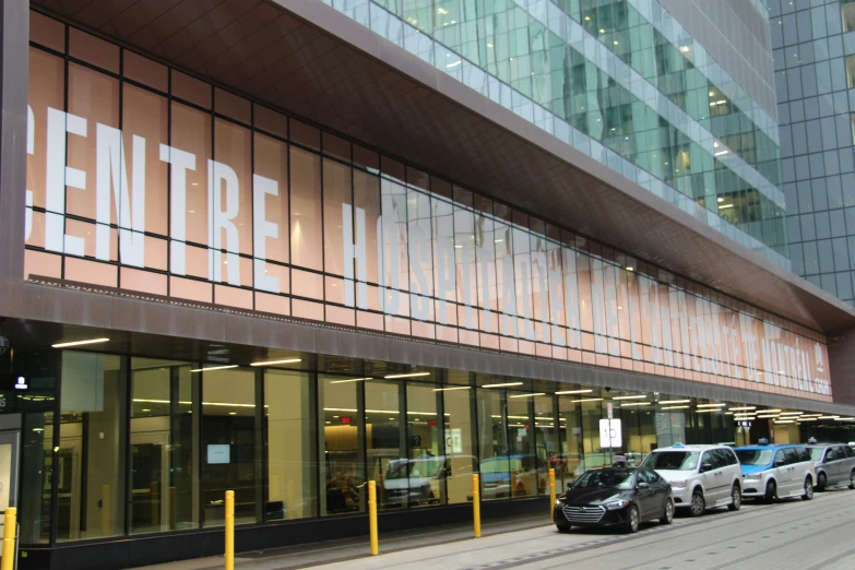 a tall brown and tan building sitting next to two cars