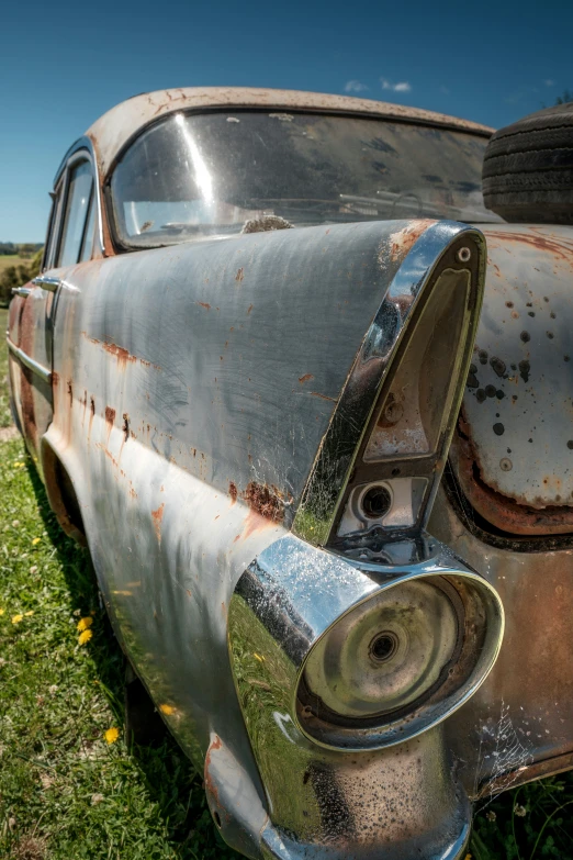 a rusty old car in a field of grass