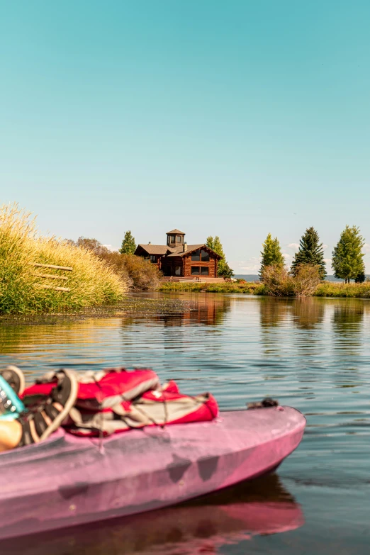 a single pink kayak sitting on the edge of a lake