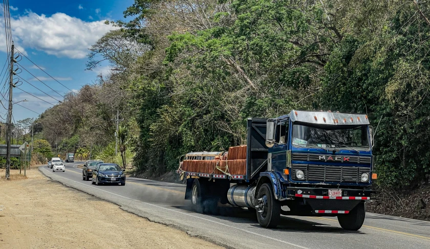 a large truck travels down the road in front of a police car