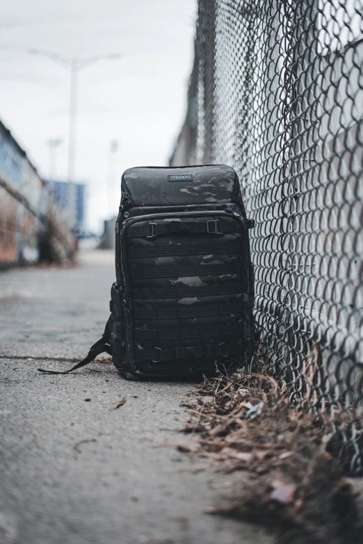 a backpack is leaning against the fence by itself