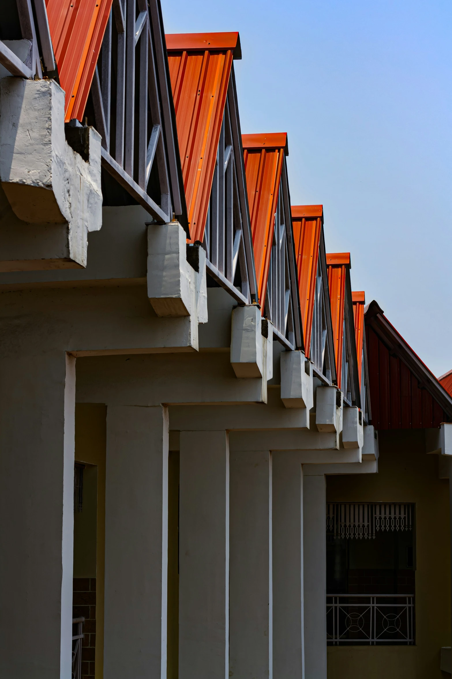 a row of orange colored roof tops over white pillars