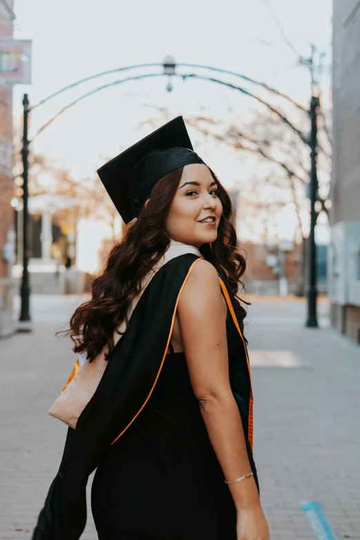 a smiling young woman in a black graduation gown and hat