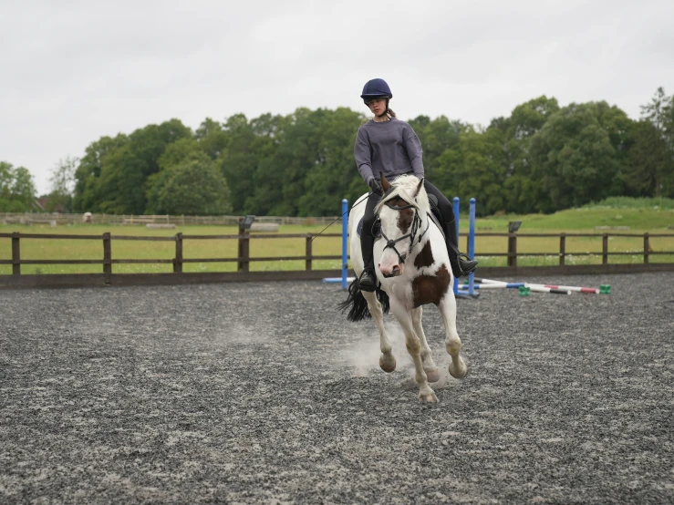 a person rides a horse in a graveled area