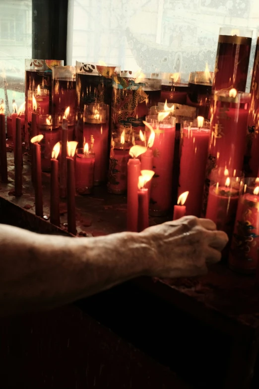 someone's arm resting on top of a table surrounded by burning candles