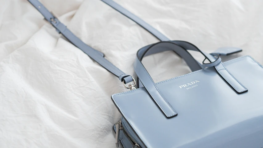 a blue handbag is on the bed with a strap