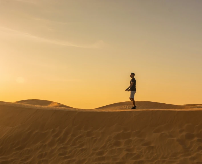 a person stands on the sand dunes in the desert