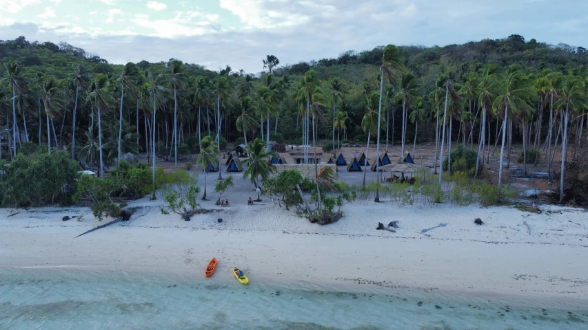 several people are standing on the sand and playing with surf boards