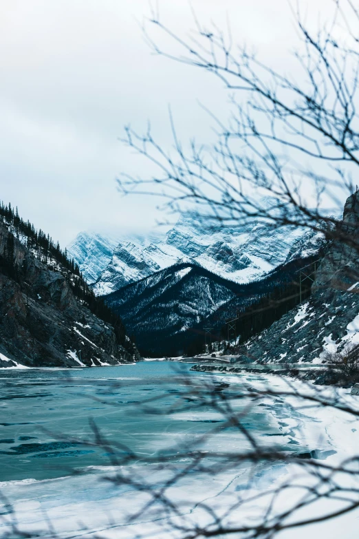 an icy lake with some snowy mountains in the background