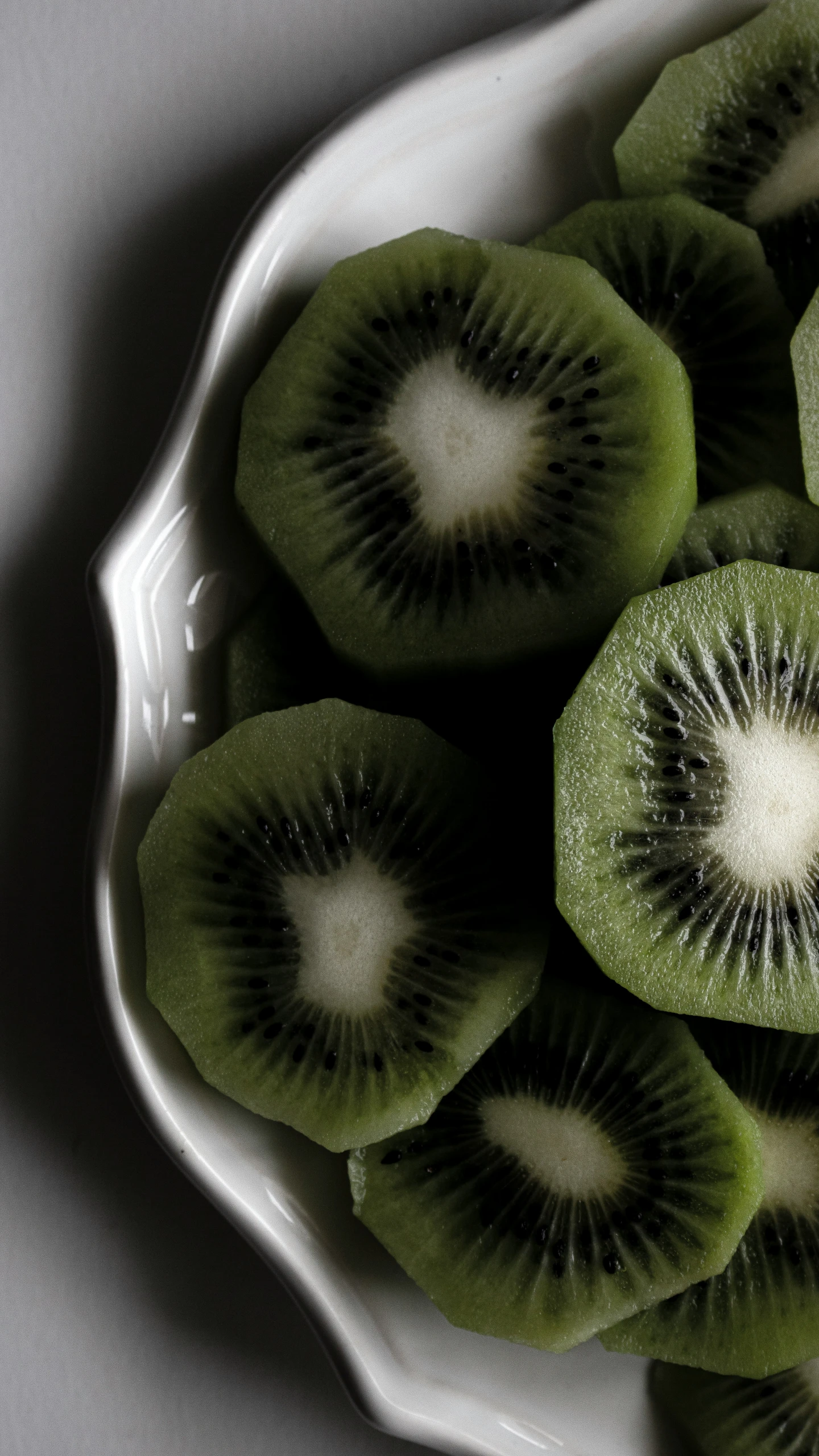 a white bowl with several kiwi slices cut into slices