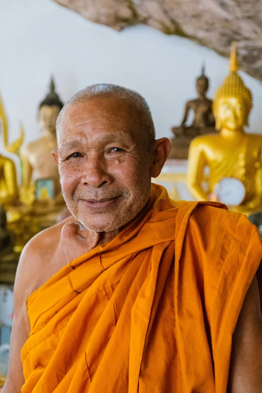 an older man smiling with orange robe on