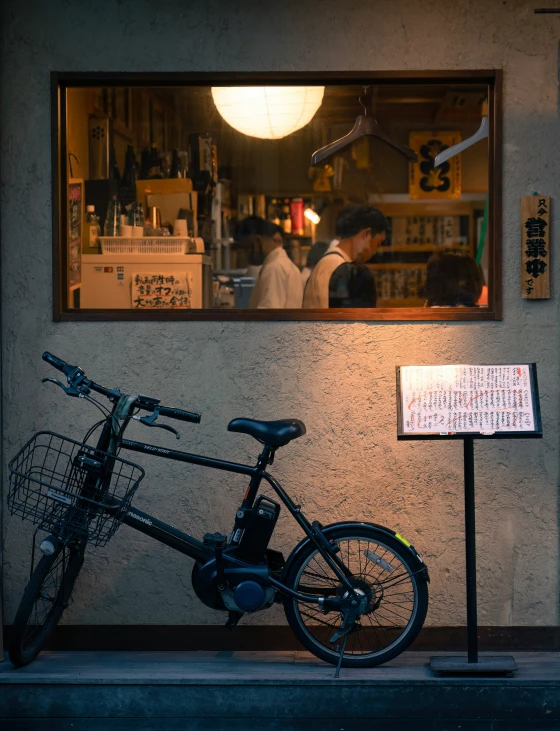 a black bicycle parked against the side of a wall with restaurant sign