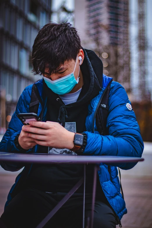 a man wearing a mask checks his phone