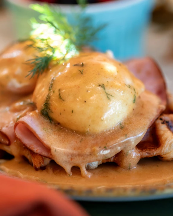 a plate with pancakes covered in ham, cheese and sauce