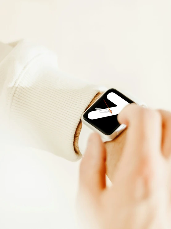 a hand holds a smart watch with a small arrow on it