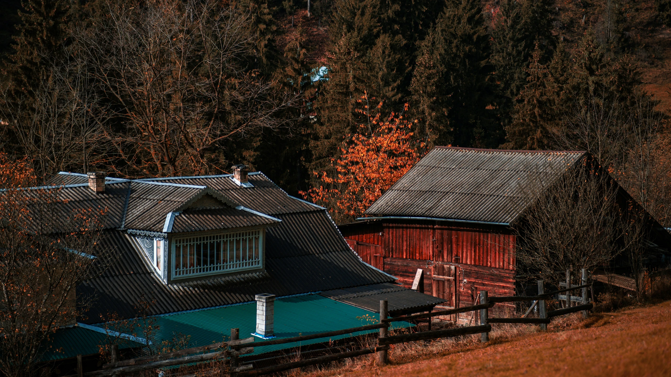 a red house sits in front of a hill and trees