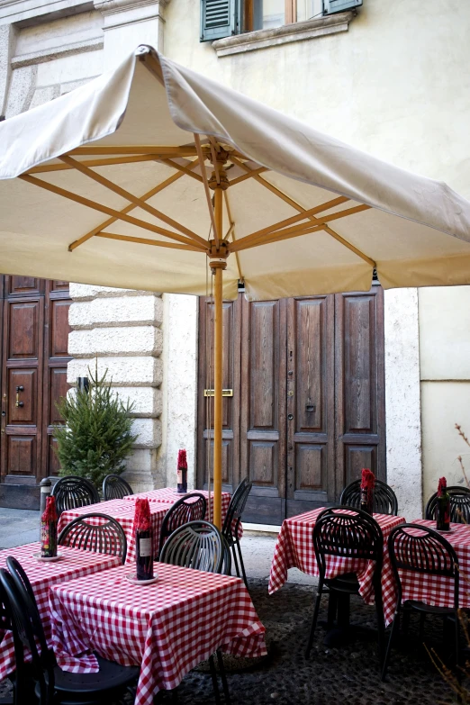 a restaurant patio with tables and chairs covered by an umbrella