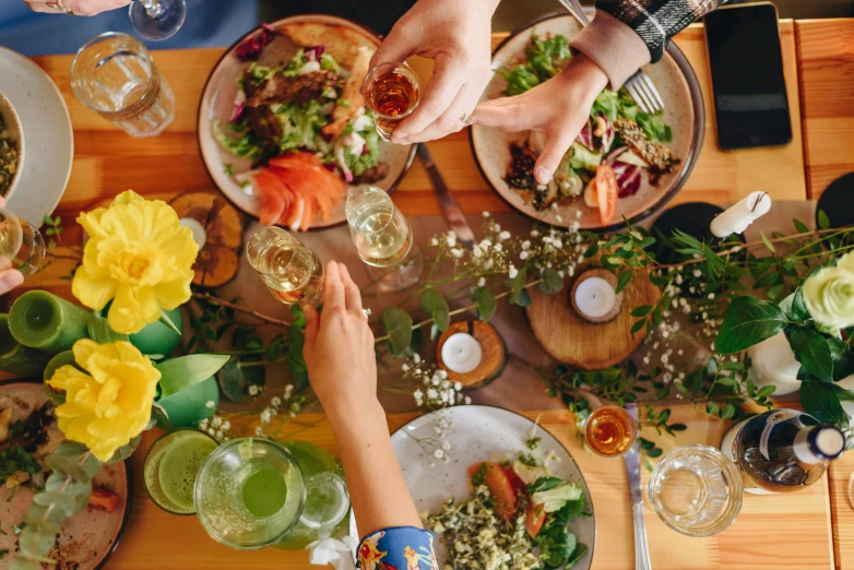 several people sit at a wooden table with food