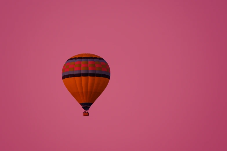 an orange and purple  air balloon in the pink sky