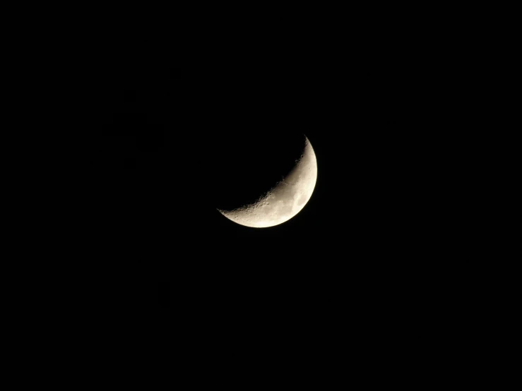 a half moon seen in the dark of night with the light off