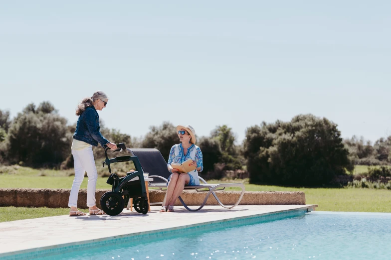 two women sitting on top of a bench by a pool