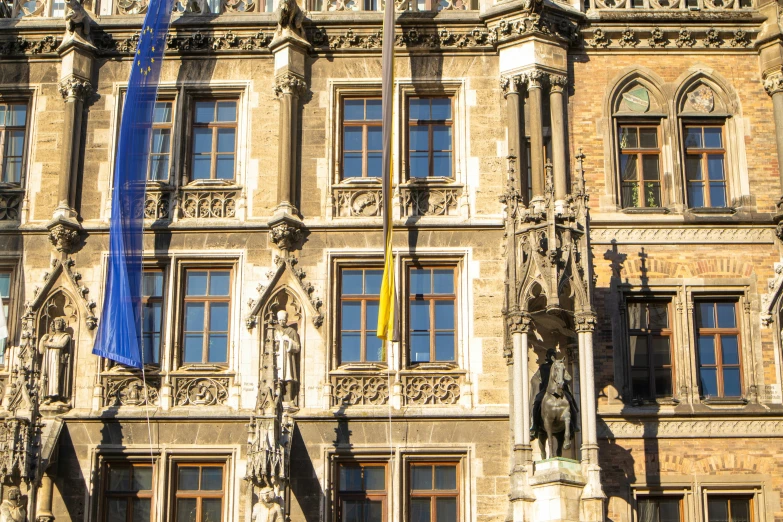 an old stone building with statues and blue banners on the front