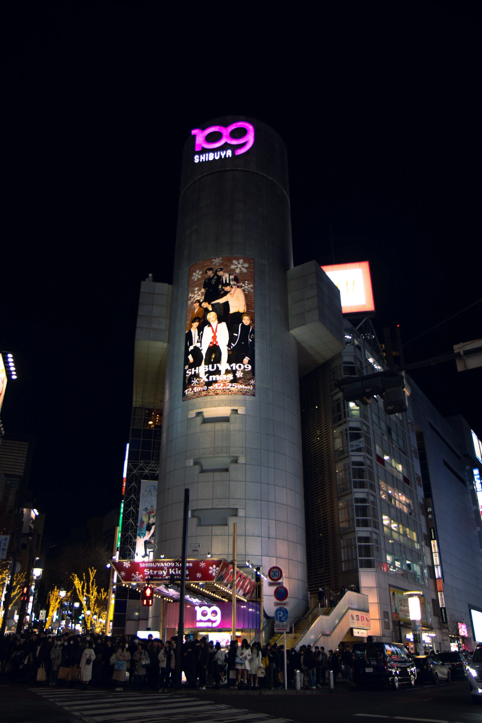 a group of people at night in front of some tall buildings