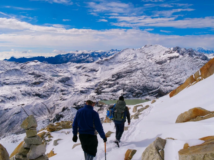 people trekking up snowy mountain in mountains