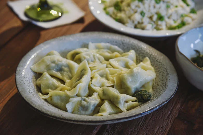 a bowl of dumpling noodles sits in front of two plates of rice