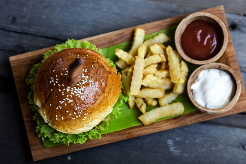 a plate with a large hamburger, french fries and sauces