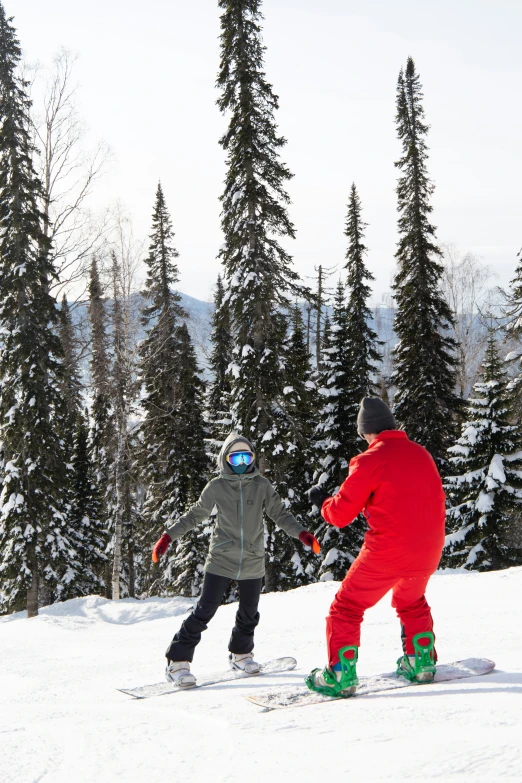 two people are skiing on a slope surrounded by trees