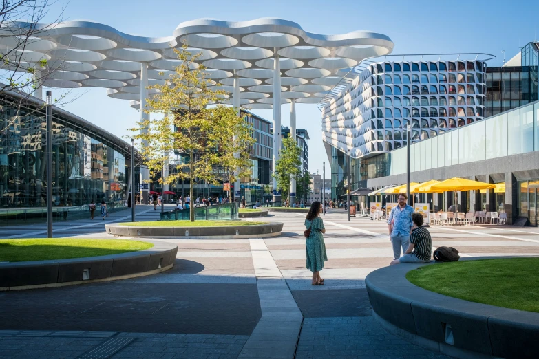 people walking in a square near a group of white poles